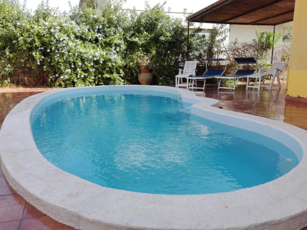 a swimming pool with blue water in a backyard at Appartamenti Villa Elisa in Bosa