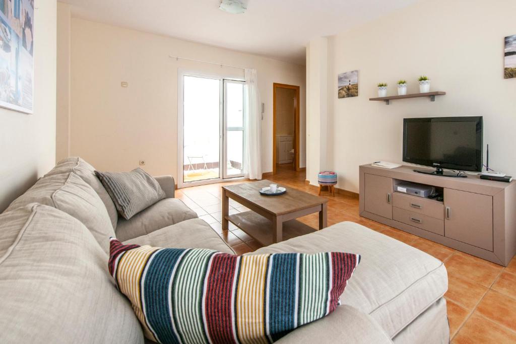 a living room with a couch and a flat screen tv at Oliastur1 Sunset Beach El Cotillo in El Cotillo