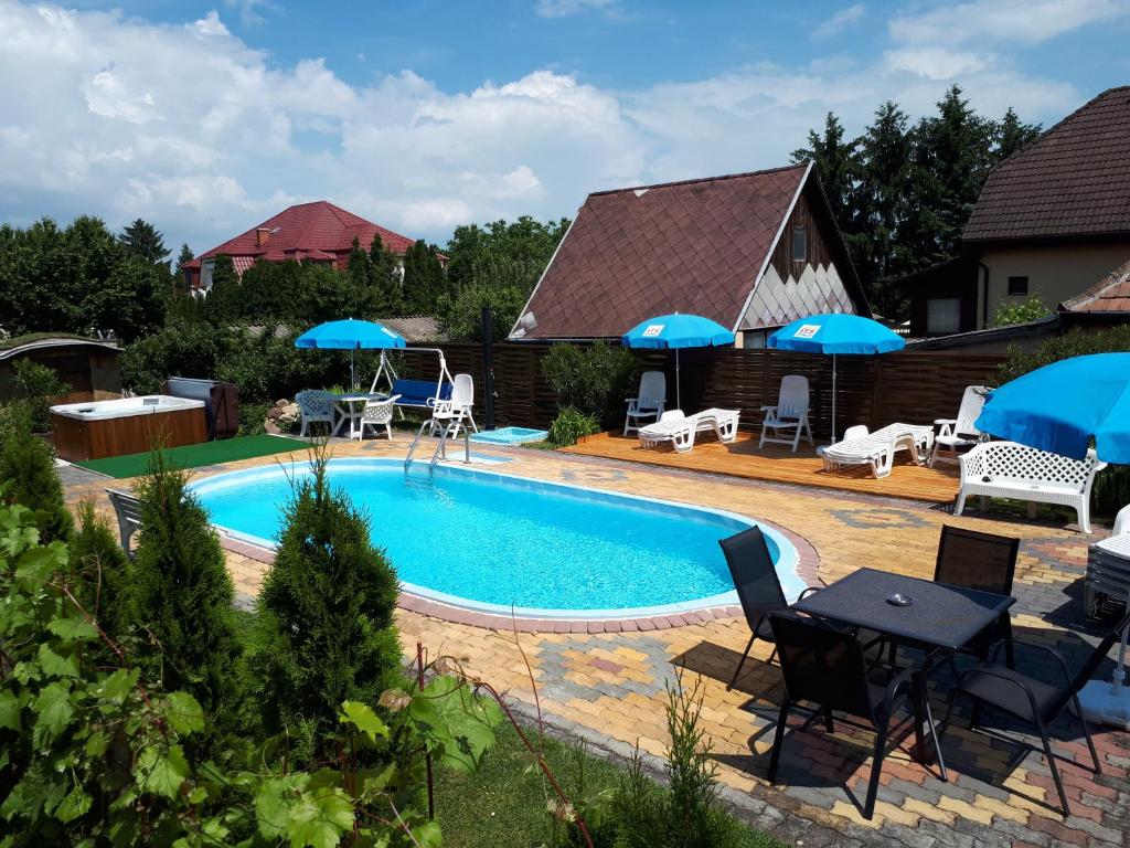 una piscina con mesa, sillas y sombrillas en Holp Panzio en Balatonföldvár