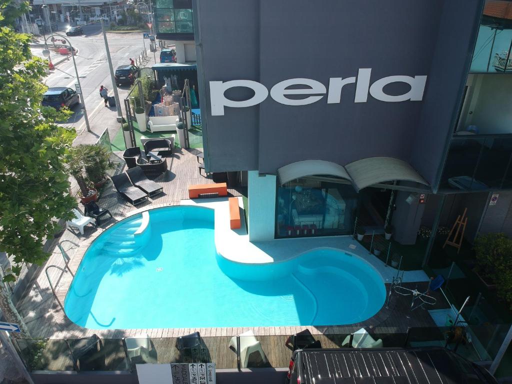 einen Blick über einen Pool vor einem Perica-Gebäude in der Unterkunft Hotel Perla in Riccione