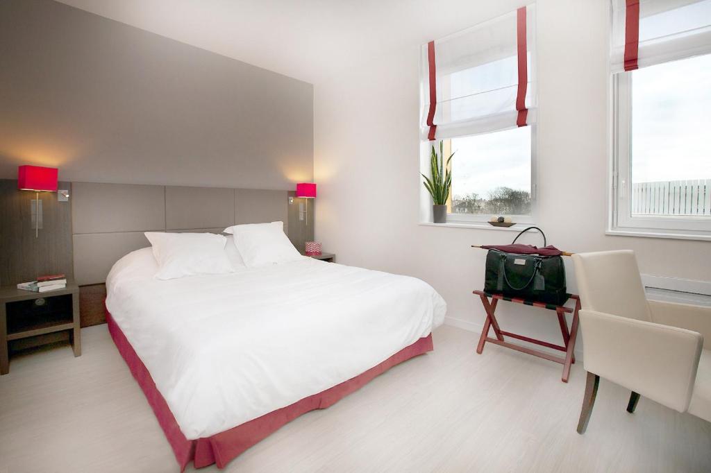 een slaapkamer met een groot wit bed en 2 ramen bij Residhome Reims Centre in Reims