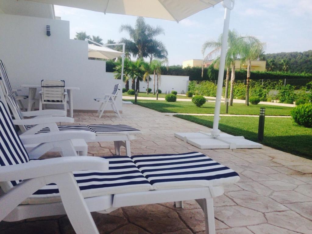 patio con sedie bianche e ombrellone di Dani's residence a Supersano