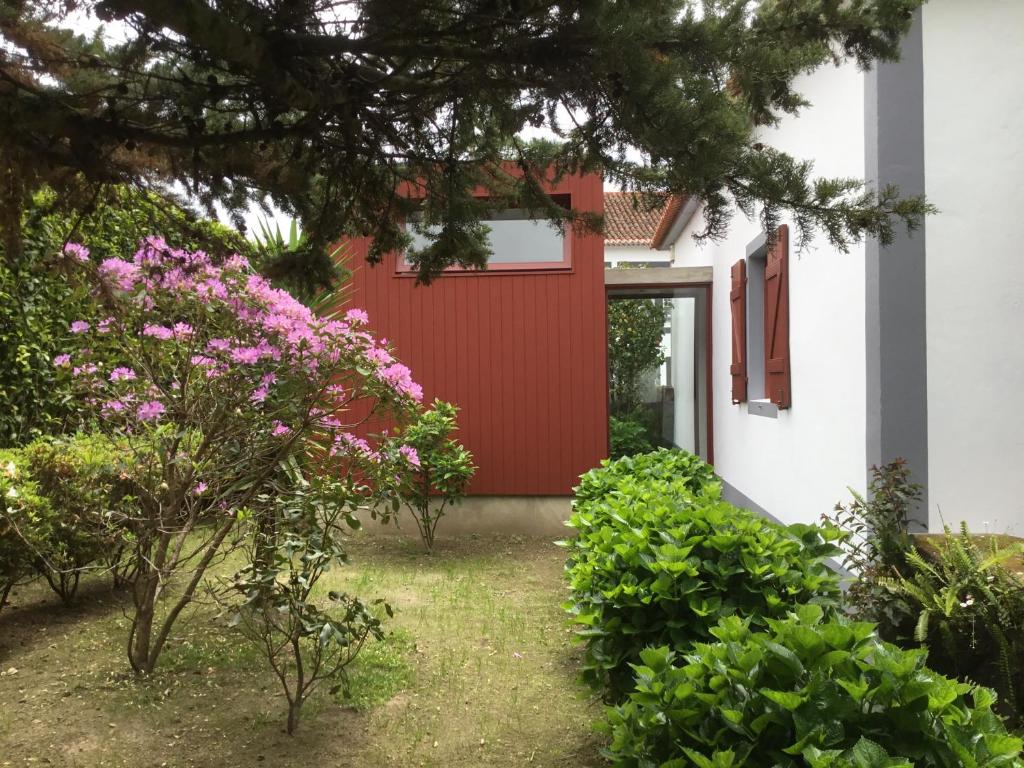 eine rote Tür auf einem weißen Haus mit Blumen in der Unterkunft Casa da Igreja Velha in Furnas