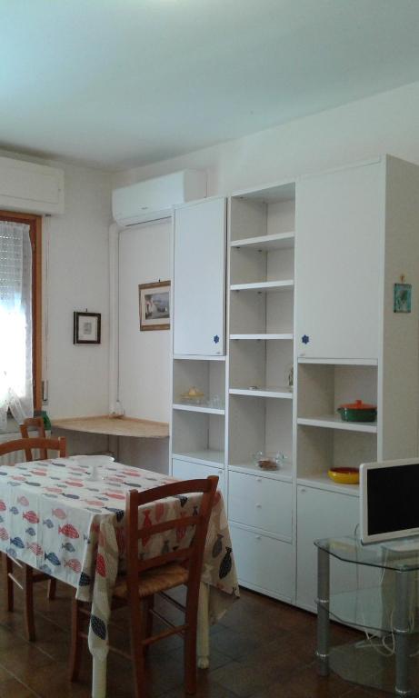 une salle à manger avec une table et des armoires blanches dans l'établissement Cala Cicala, à Levanto