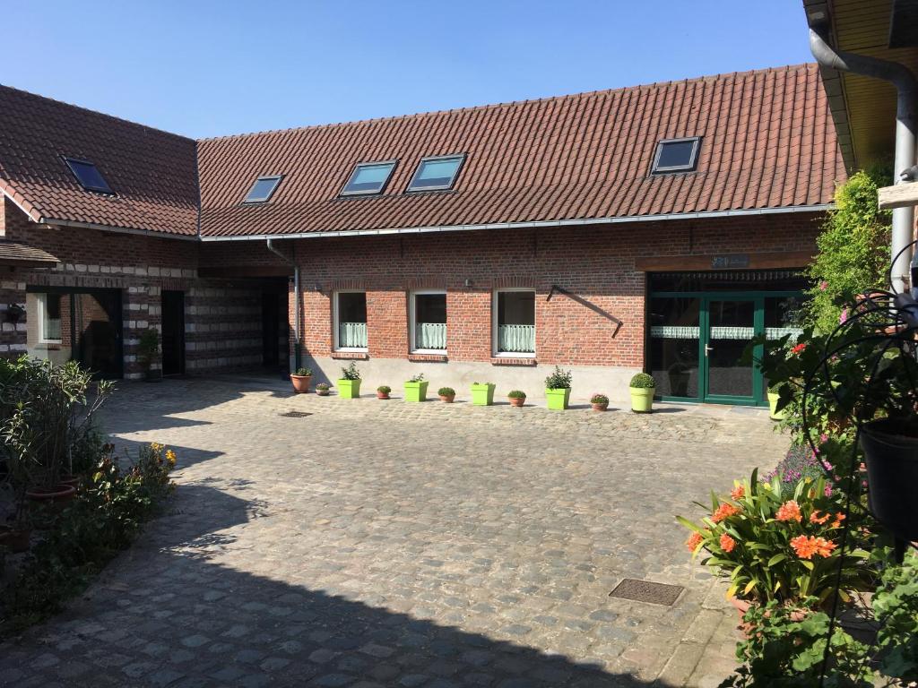 a brick building with a courtyard in front of it at Ferme BROCART in Bouvines