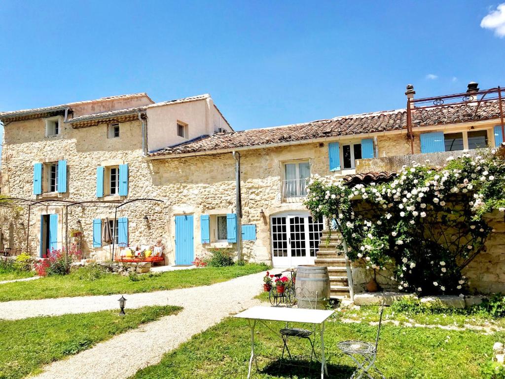 uma antiga casa de pedra com portas azuis e um quintal em Domaine de La Brave em Pernes-les-Fontaines
