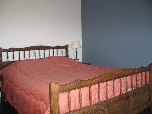 um quarto com uma cama de madeira e um cobertor vermelho em Les Hortensias em La Poultière