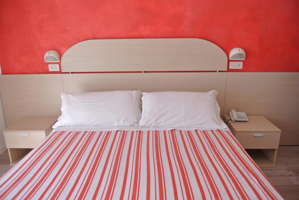 a bed in a room with a red wall at Hotel Bologna in Lignano Sabbiadoro