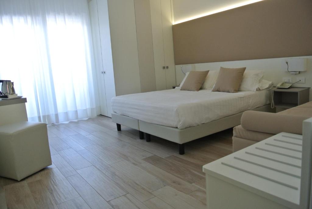 a bedroom with a white bed and a couch at Hotel Bologna in Lignano Sabbiadoro