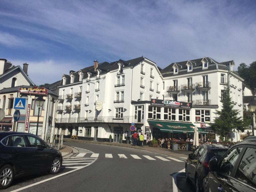 een straat met auto's geparkeerd voor gebouwen bij Hotel Bouillon in Bouillon