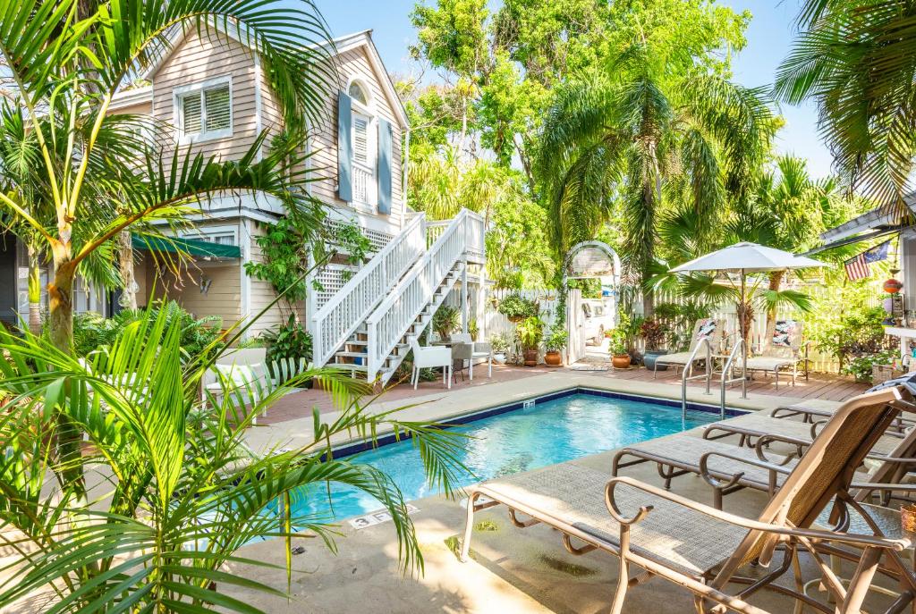 a house with a swimming pool with chairs and trees at Andrews Inn & Garden Cottages in Key West