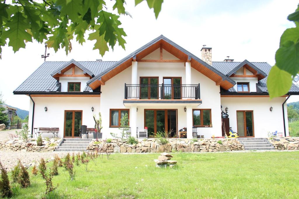 une maison avec une pelouse verte devant elle dans l'établissement Sielski Zakątek, à Cisna