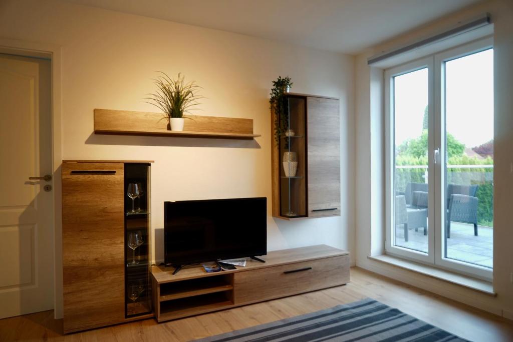 a living room with a flat screen tv on a wooden entertainment center at M&A Ferienwohnungen Oberbayern in Peiting