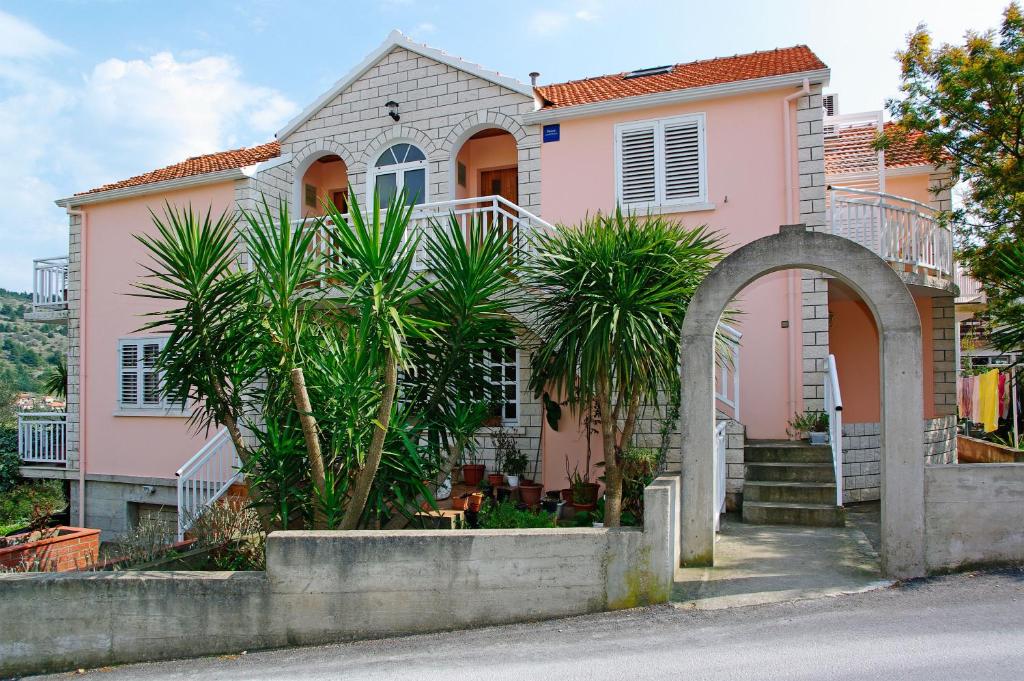 a pink house with palm trees in front of it at Apartments Julija in Vela Luka