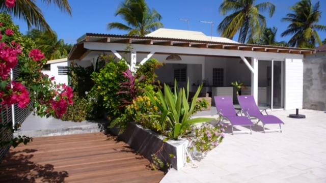 a patio with purple chairs and flowers and a house at Villa Acajou in Saint-François