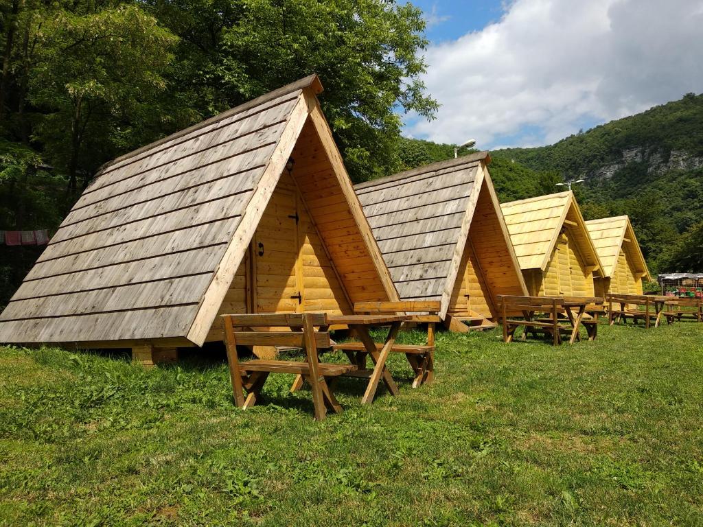 una fila de cabañas de madera sentadas en el césped en Camp Vrbas, en Rekavice