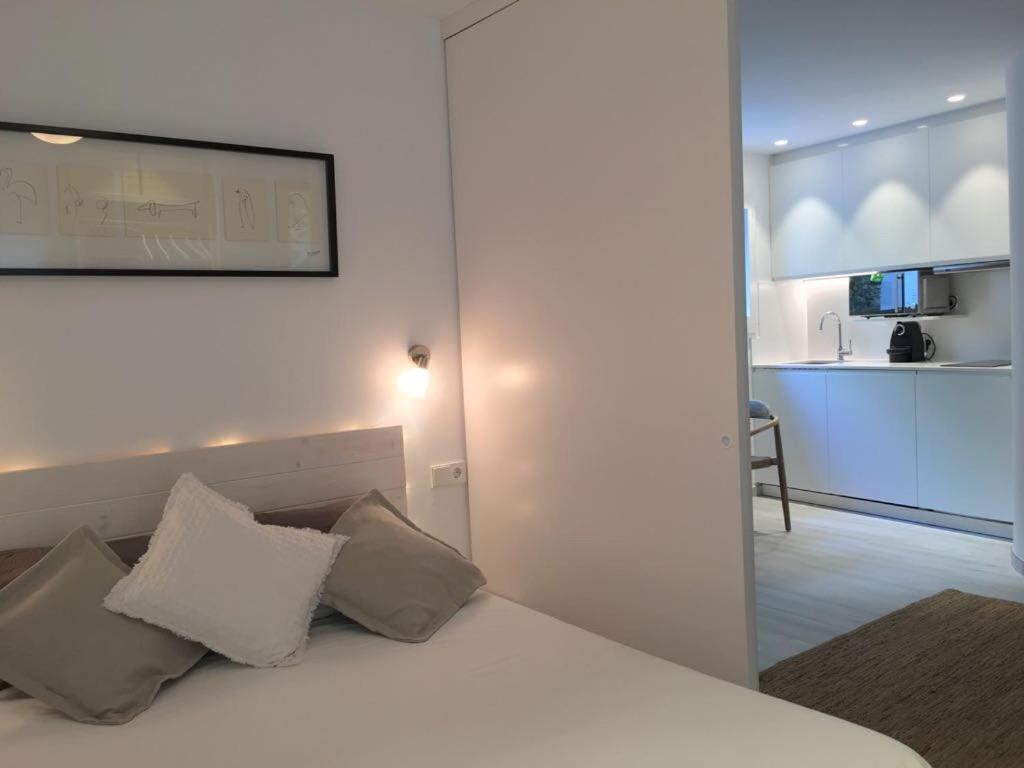 a bedroom with a bed with pillows and a kitchen at Smart Studio Cadaqués Sa Guarda in Cadaqués