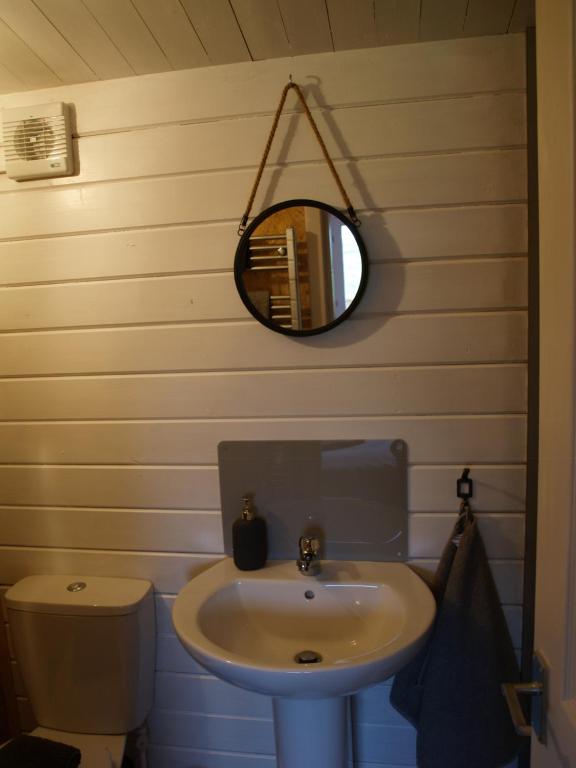 ein Bad mit einem Waschbecken und einem Wandspiegel in der Unterkunft The Cosy Cabin in Portree