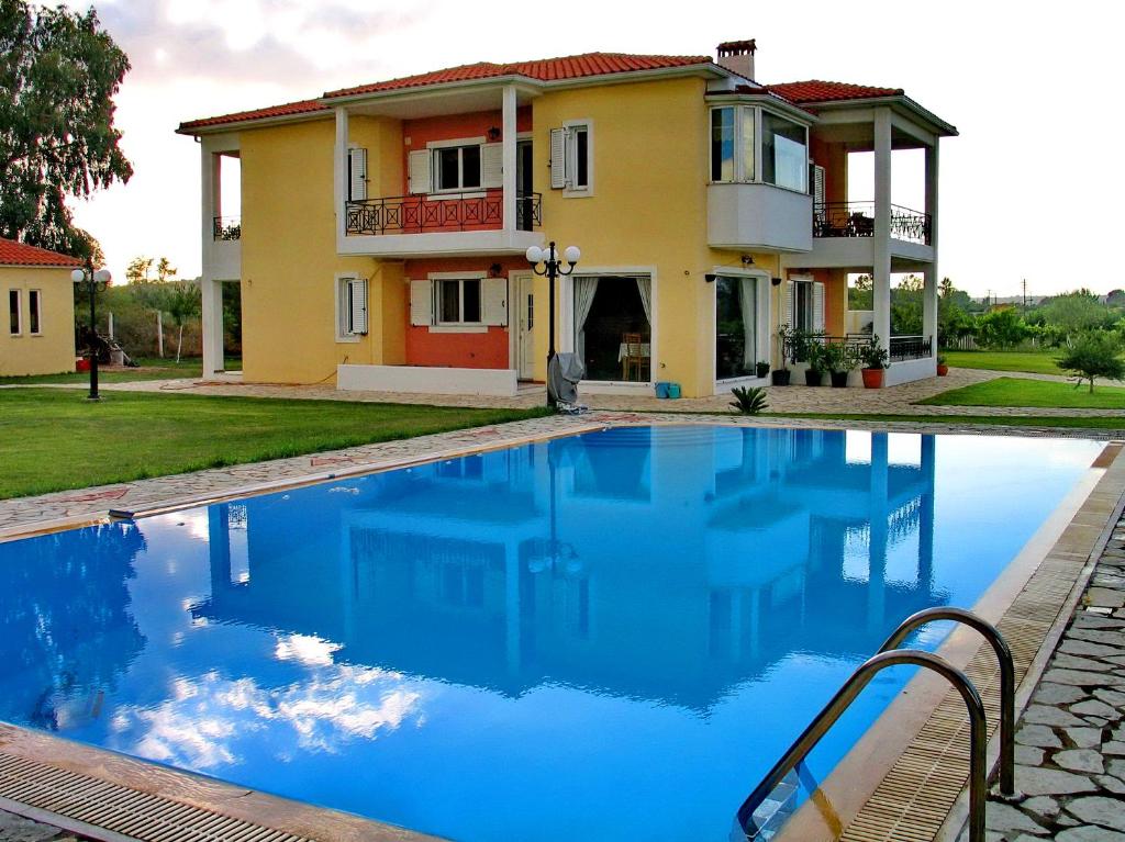 a villa with a swimming pool in front of a house at Villa Giannopoulos in Áyios Ioánnis