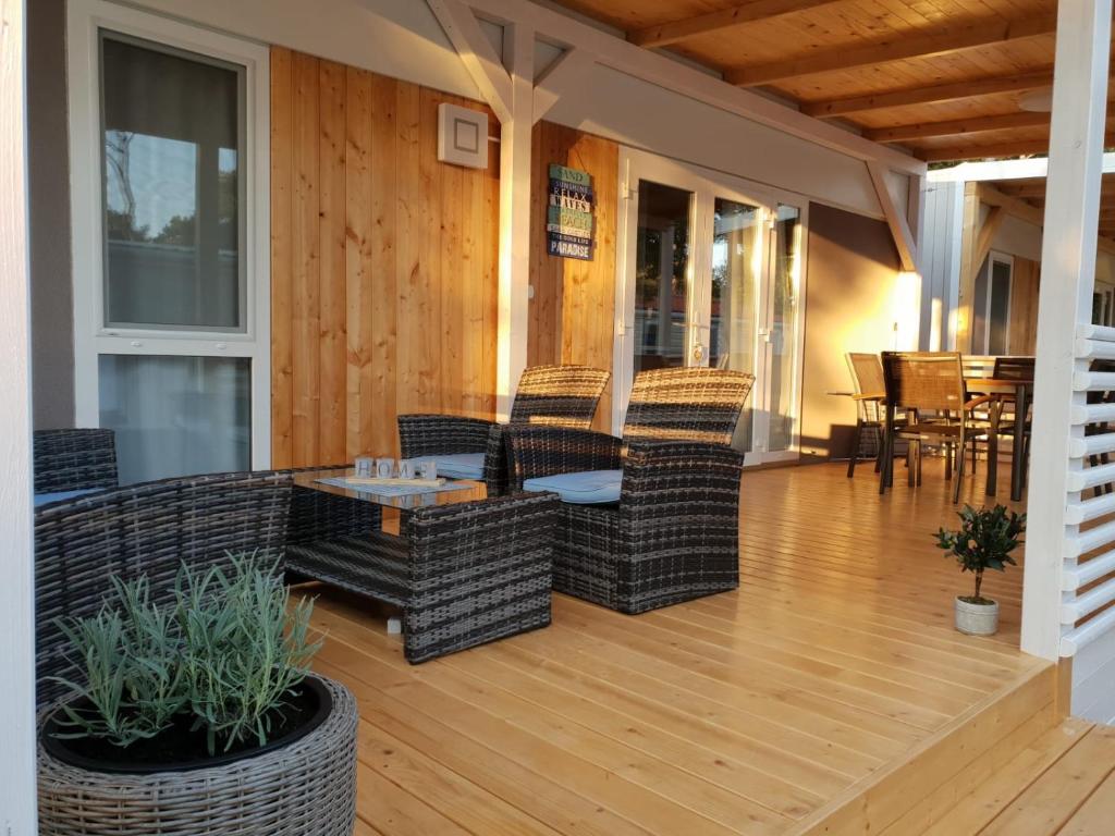 a screened porch with wicker chairs and a table at Mobile Home Seahorse Camp Soline in Biograd na Moru