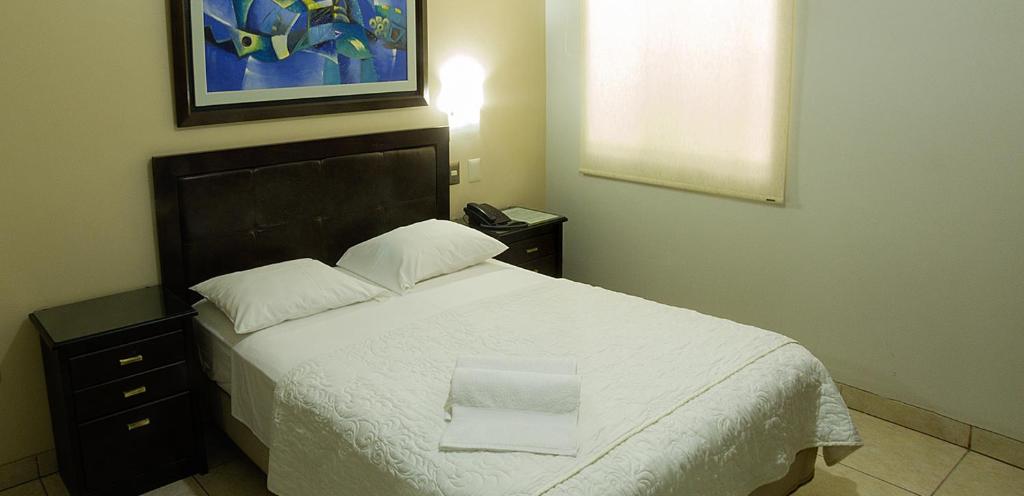 a bedroom with a large bed with a white blanket at Rivera del Rio Hotel in Piura