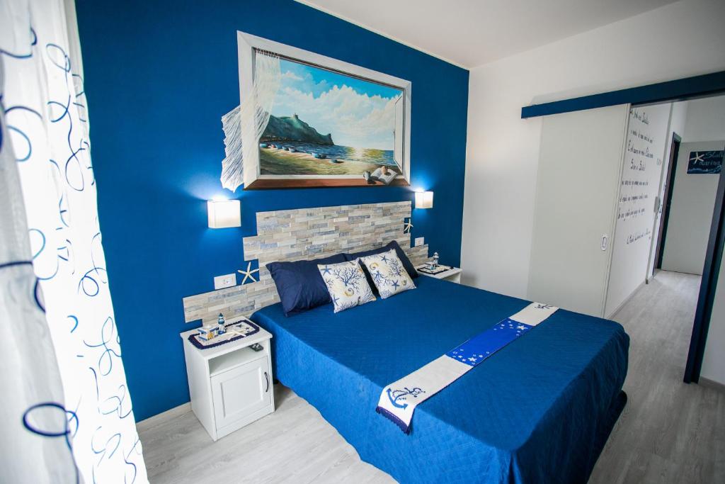 een blauwe slaapkamer met een bed en een schilderij aan de muur bij La casa del pescatore in Oliveri