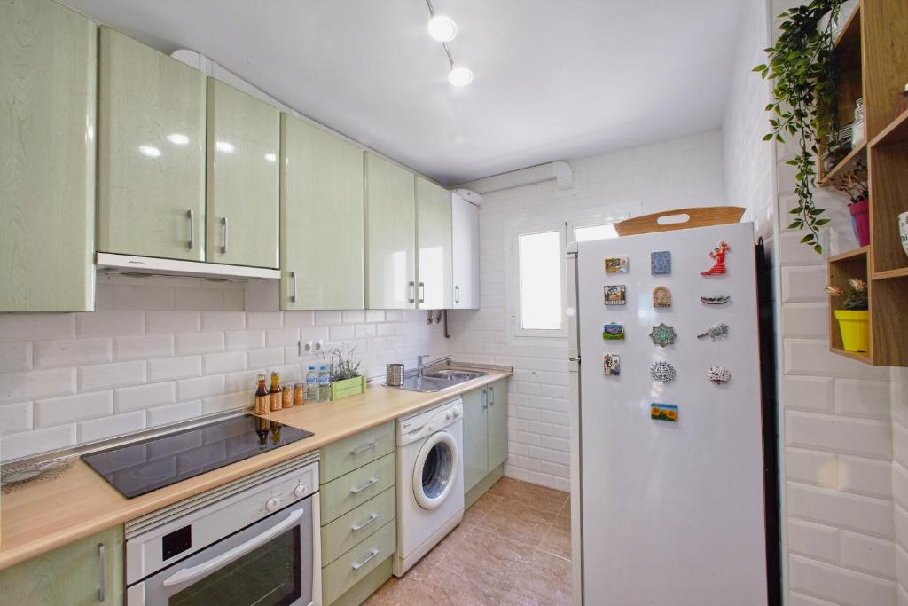 kuchnia z zielonymi szafkami i białą lodówką w obiekcie Casa Volare- estilo y relax en pleno casco antiguo w Maladze
