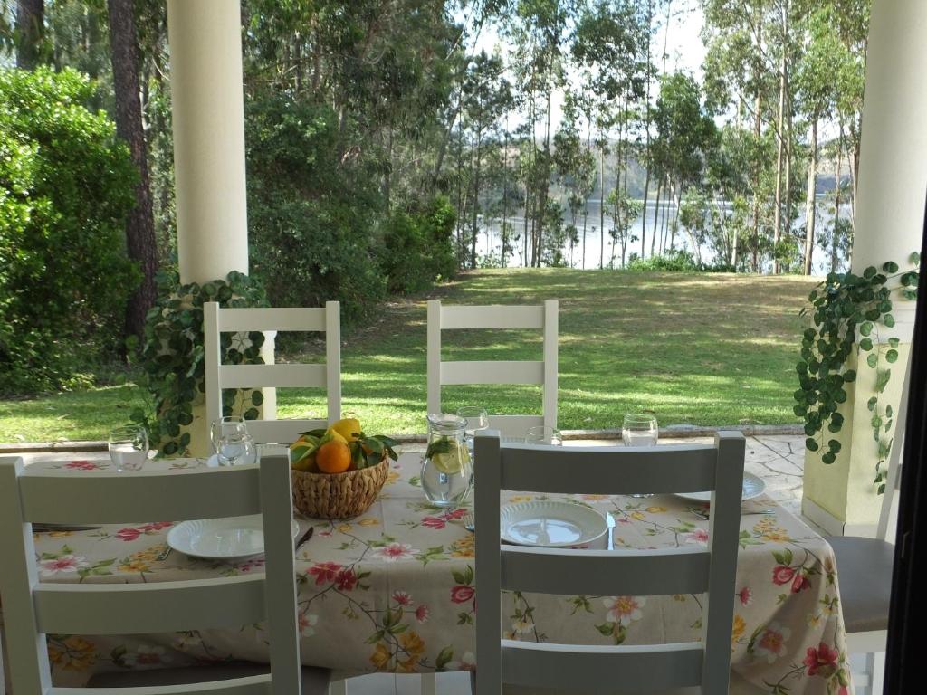 a table with white chairs and a table with fruit on it at Apartamento Rio Zêzere in Ferreira do Zêzere