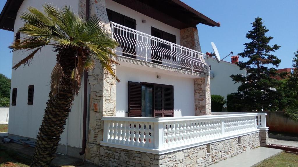 Cette maison blanche dispose d'un balcon et d'un palmier. dans l'établissement Villa Leona, à Medulin