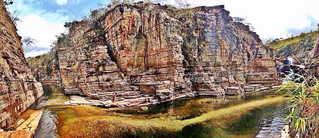 a painting of a large rocky mountain with a river at Canyon Cascata Eco Parque in Capitólio