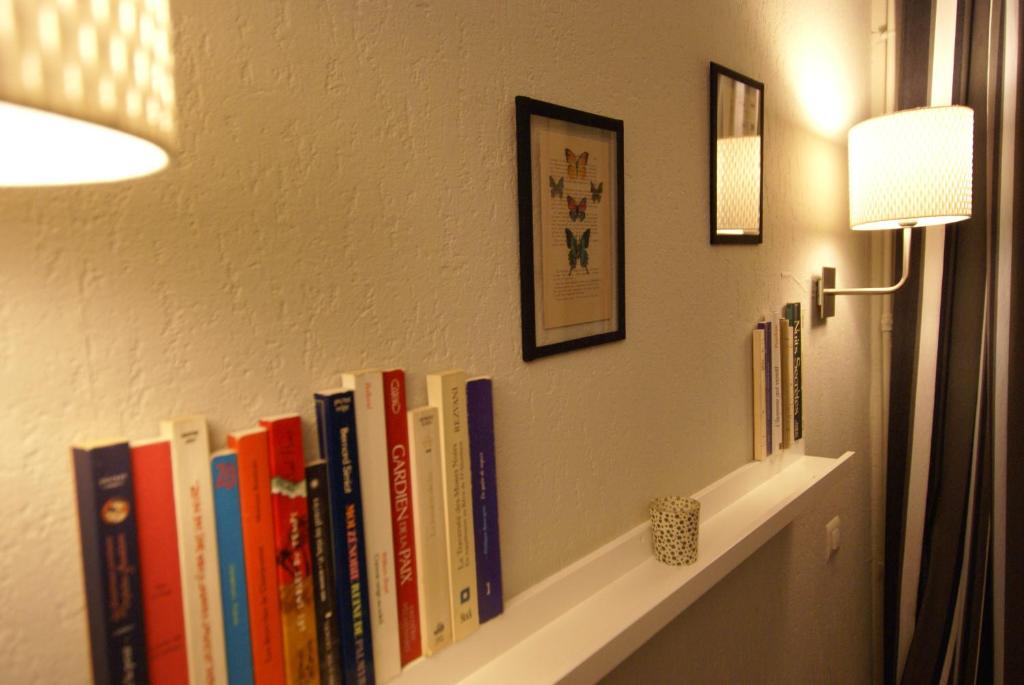a shelf with books on a wall with a lamp at Hotel de la Placette Barcelonnette in Barcelonnette