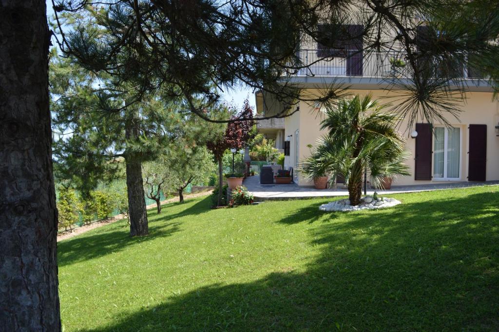 Blick auf ein Haus mit Bäumen im Hof in der Unterkunft Maison Margot in Acquaviva Picena