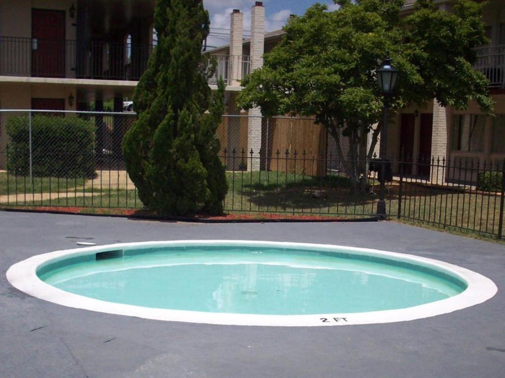 a small pool in a parking lot with a tree at Days Inn by Wyndham Dothan in Dothan