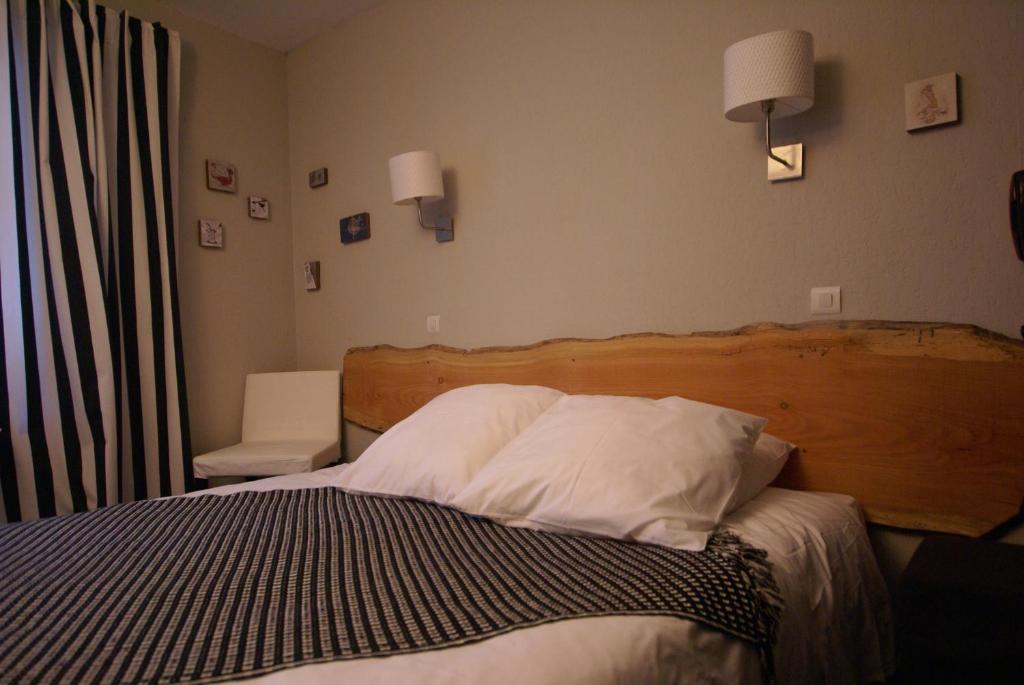 a bedroom with a bed with a wooden headboard at Hotel de la Placette Barcelonnette in Barcelonnette