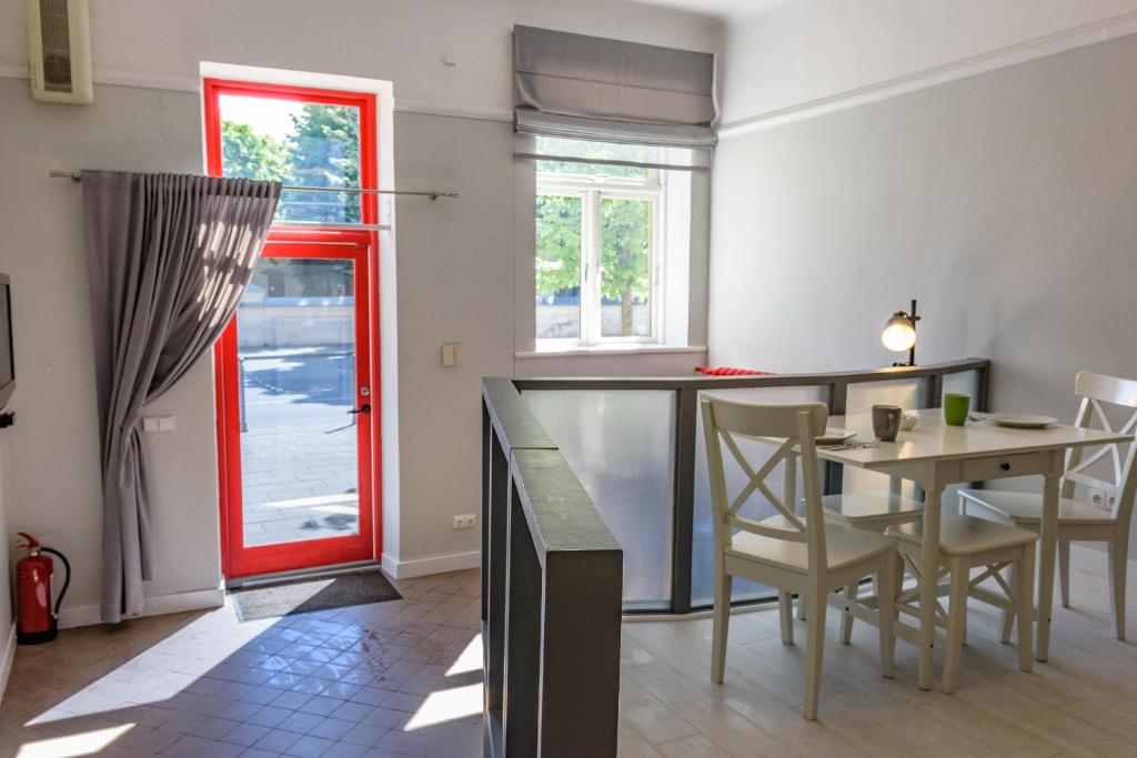 cocina con puerta roja, mesa y sillas en Studio 59 en Kaunas