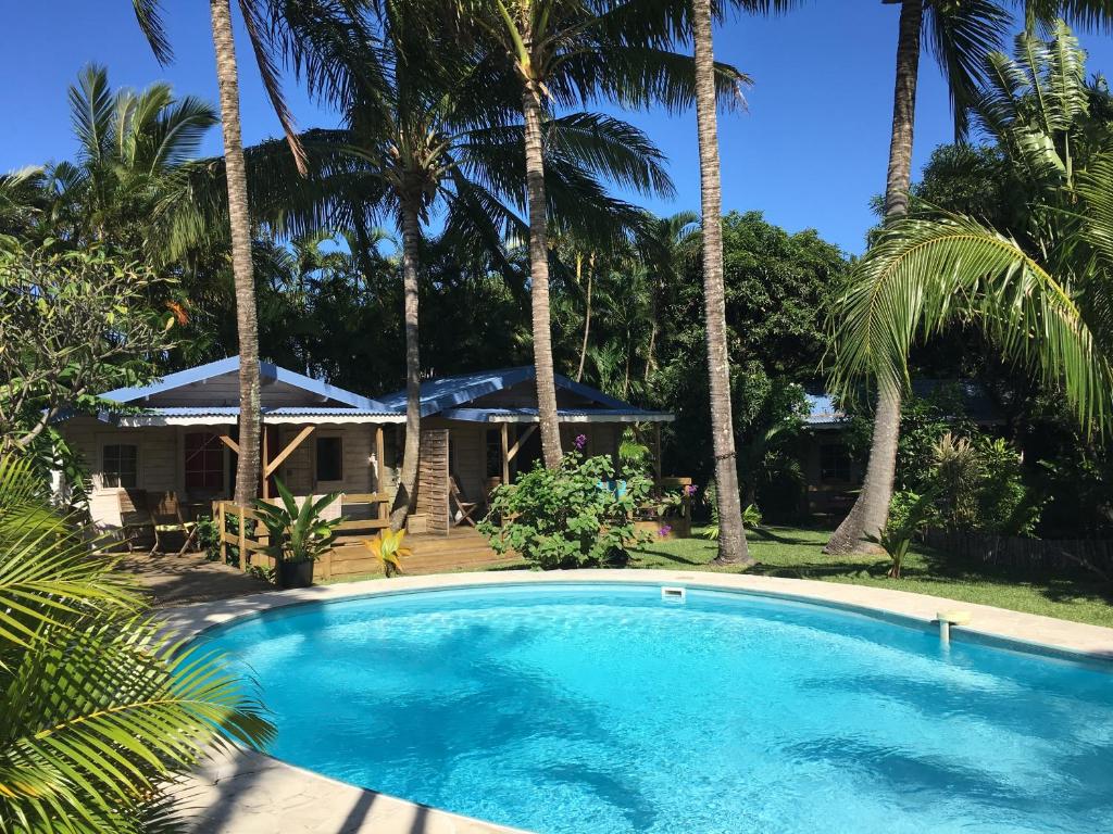 - une piscine en face d'une maison avec des palmiers dans l'établissement La Rose du Sud, à Saint-Joseph