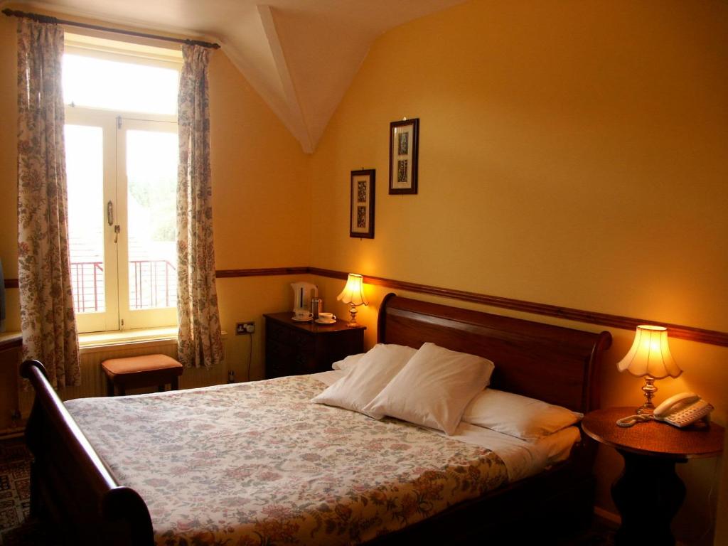 Chequers Inn Hotel في فورست رو: غرفة نوم بسرير ومصباح ونافذة