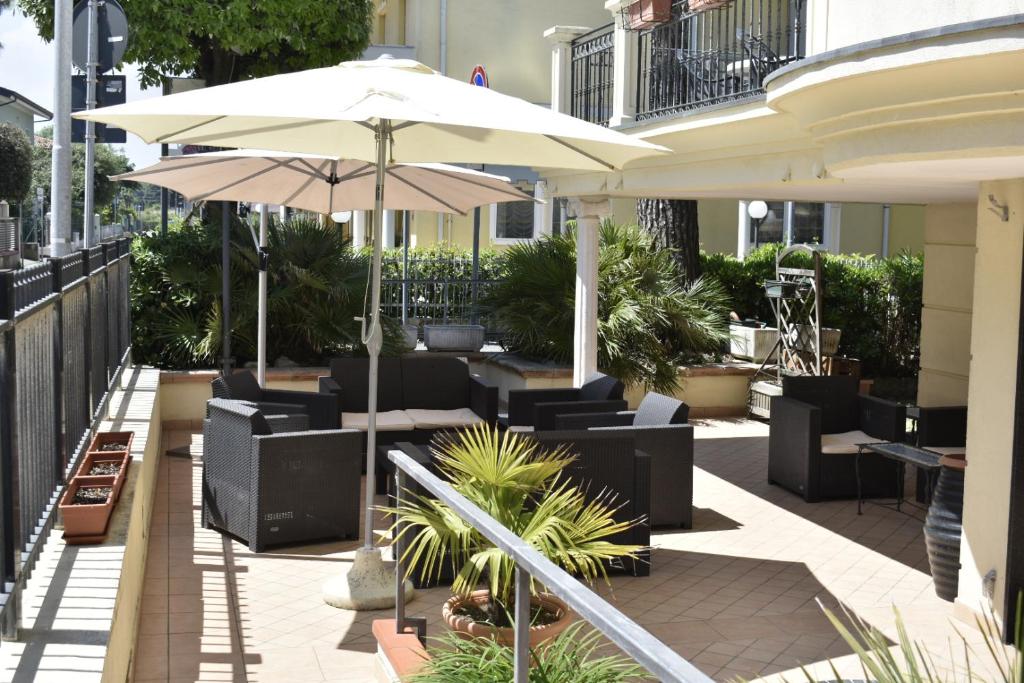 patio z krzesłami i parasolem w obiekcie Hotel Perla Verde w Rimini