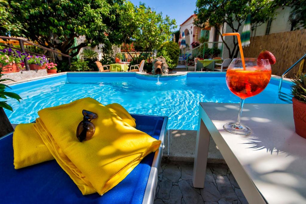 a drink sitting on a table next to a swimming pool at hotel la rondinella in Ischia
