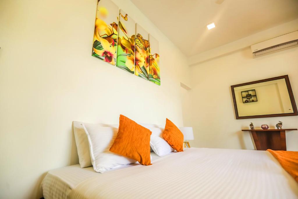 ein Schlafzimmer mit einem weißen Bett und orangefarbenen Kissen in der Unterkunft Remli Villa in Kandy