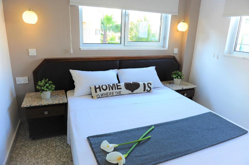 a bedroom with a large white bed with a home improvement sign on it at Napa City Apartments in Ayia Napa