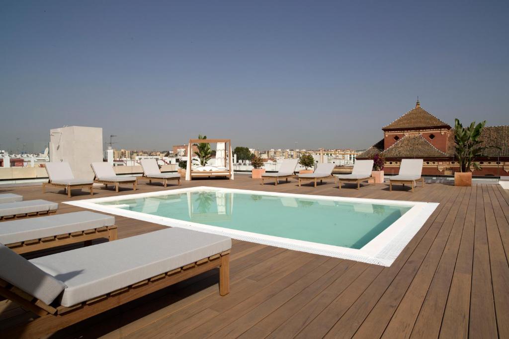 a pool on the roof of a building with lounge chairs at Zenit Sevilla in Seville