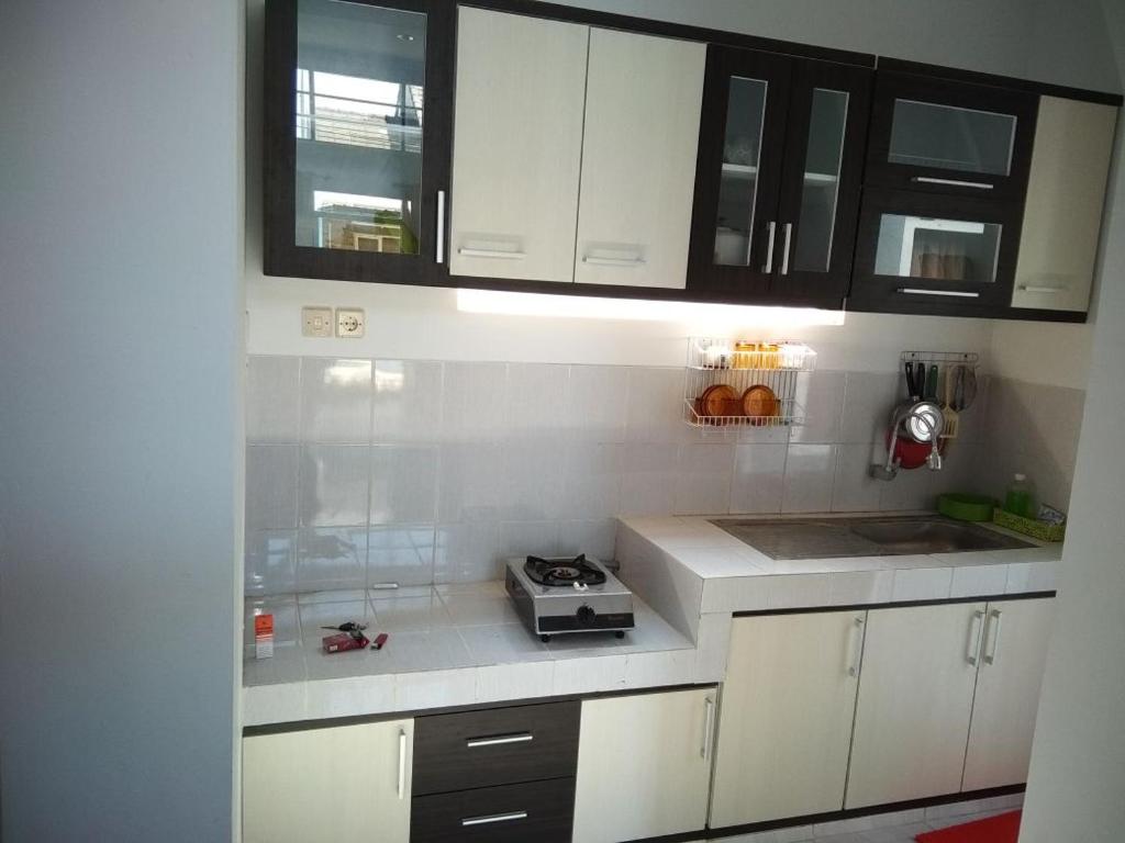 a kitchen with white cabinets and a counter top at Villa Puncak Garuda A5 in Batu