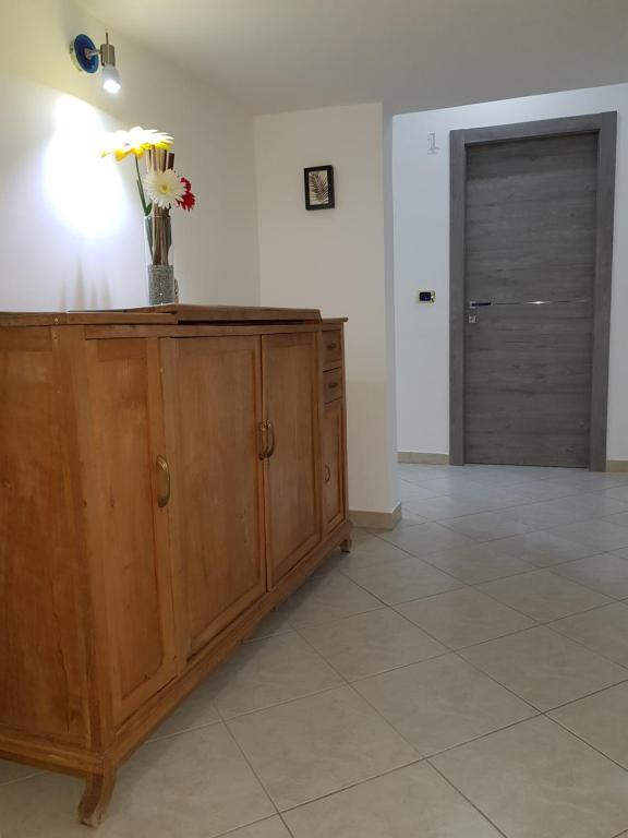 a room with a wooden cabinet with a vase of flowers on it at Holiday B&B in Vico del Gargano