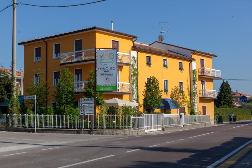 un bâtiment jaune sur le côté d'une rue dans l'établissement Hotel Bardolino, à Bardolino