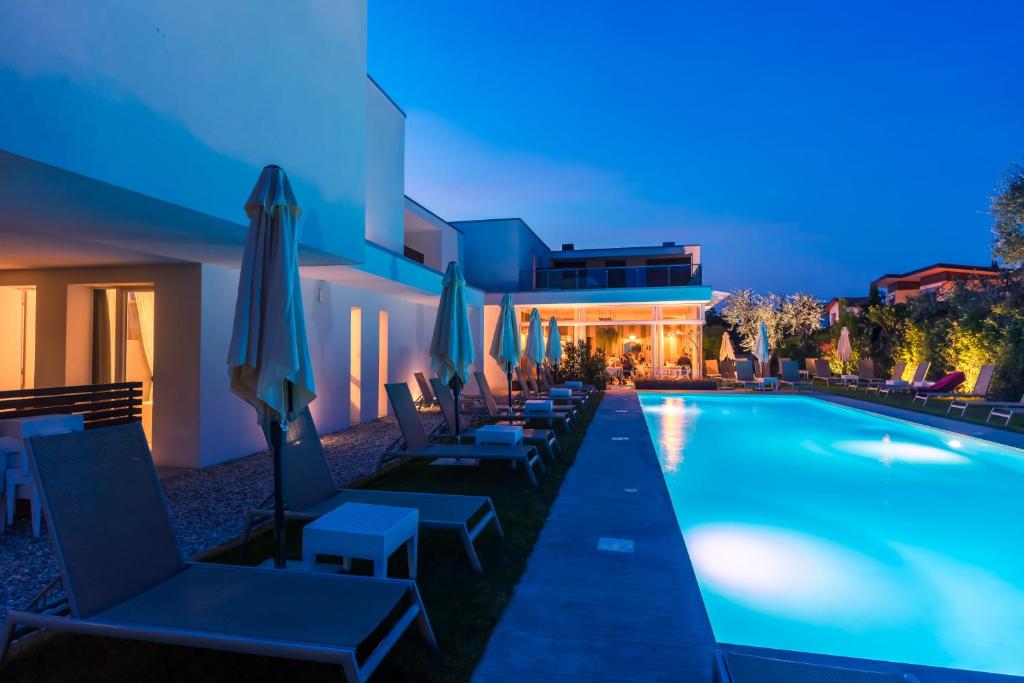 a swimming pool with chairs and umbrellas next to a building at Hotel Maximilian in Bardolino