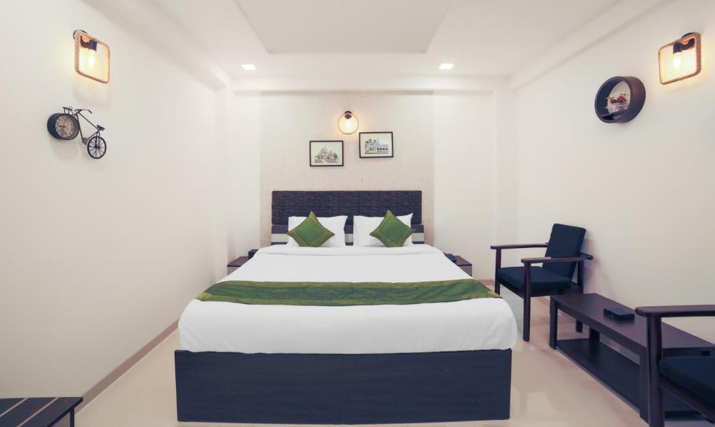 a bedroom with a large bed and a chair at Treebo Trend Chalets, Nagpur Airport in Nagpur