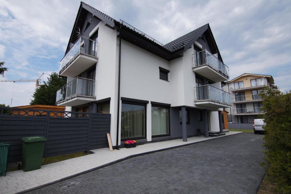 a white house with a black roof and a driveway at Paradise in Jastarnia