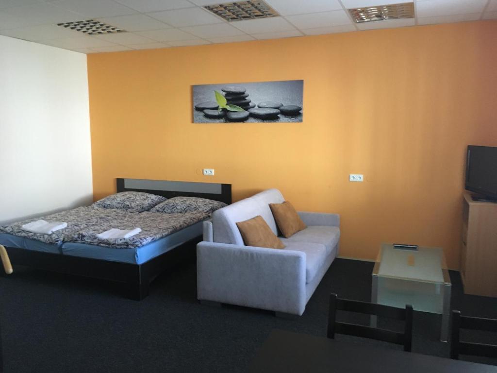 ein Schlafzimmer mit einem Bett, einem Sofa und einem Stuhl in der Unterkunft Apartment Corriger in Ústí nad Orlicí