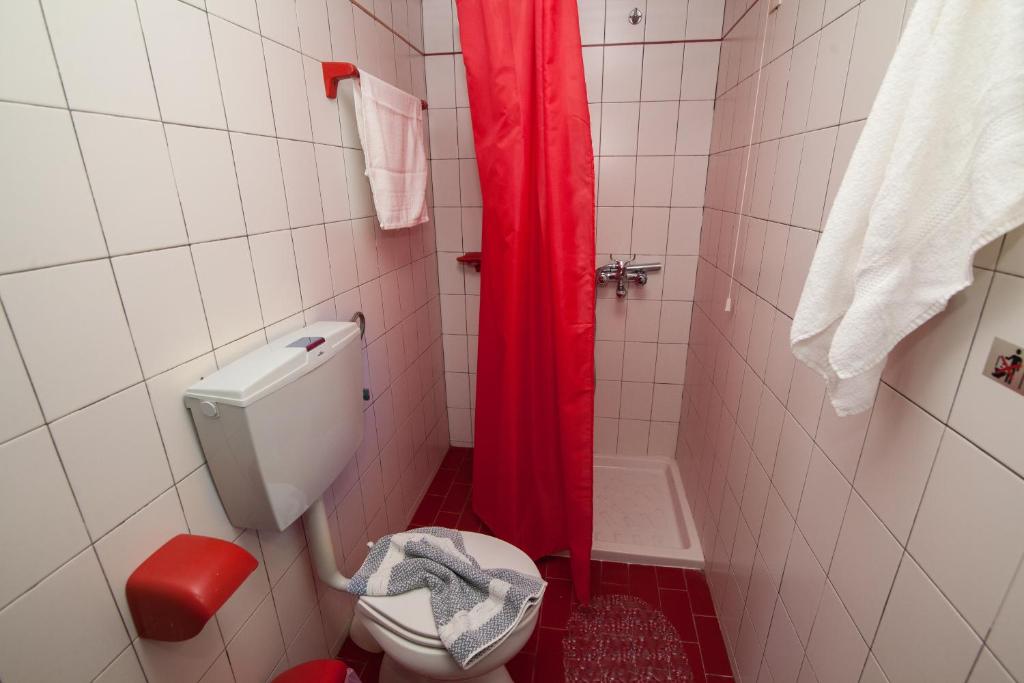 łazienka z toaletą i czerwoną zasłoną prysznicową w obiekcie Vasilakis Studios & Apartments w mieście Stalida